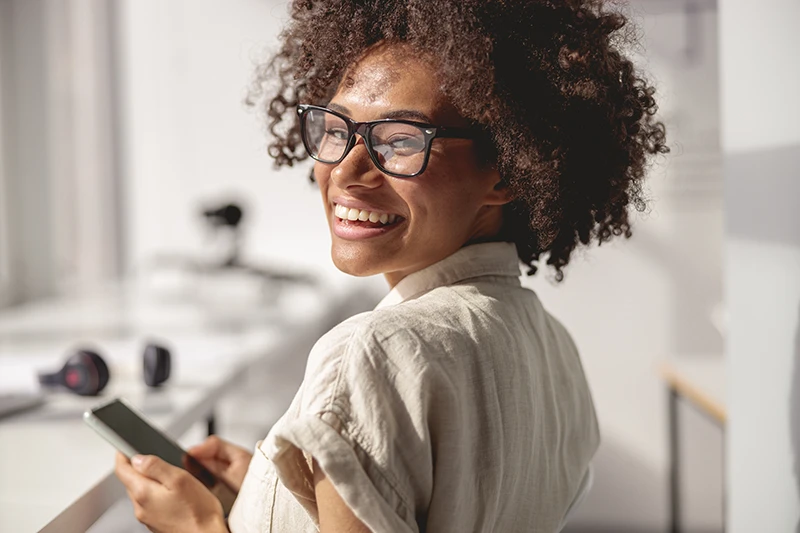 a woman smiling and wearing glasses in the office